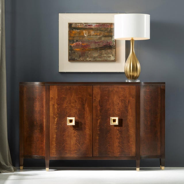 The sideboard showcases the natural elegance of figured walnut paired with refined gold leaf hardware. The bookmatched...