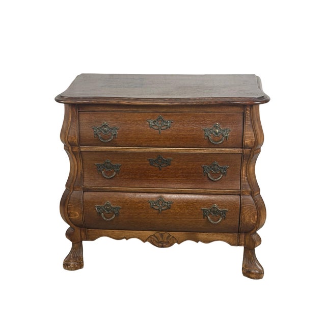 A charming vintage Dutch Baroque Revival chest of drawers featuring a sculptural bombé silhouette, richly grained oak...