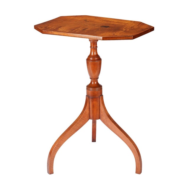 American figured maple octagonal top candle stand with an urn form turned baluster resting on arched tripod spider legs....