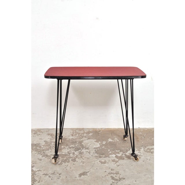 Nice 60s side table with striking steel legs on wheels. There is a red with black stripes, cotton/linen-like material on...