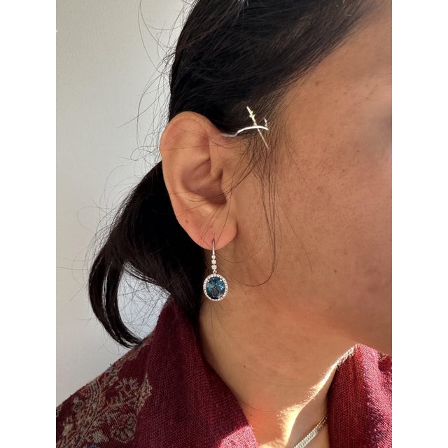 This beautiful pair of diamond halo dangles earrings feature a matched pair of london blue topaz. An art deco earring...