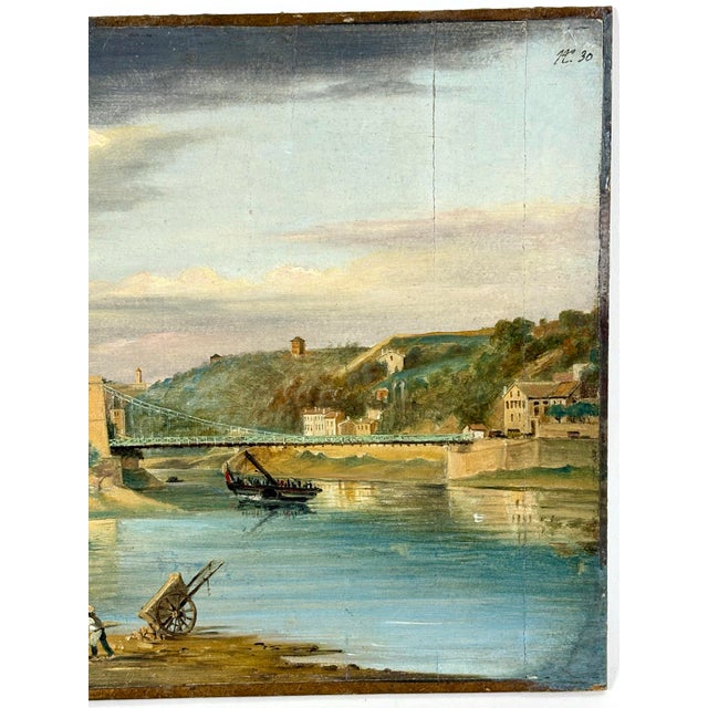 A vivid realist view of a French river with early suspension bridge connecting the two sides of a town. The oil on paper...