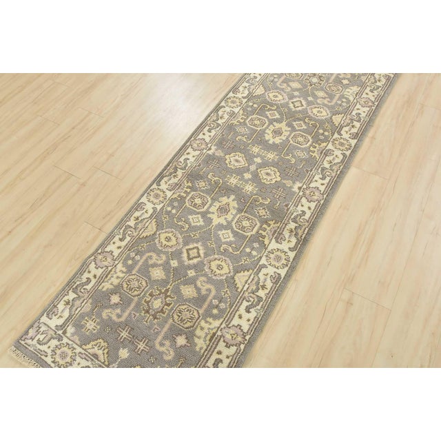 This traditional Oushak runner is hand-knotted with an all-wool pile on a cotton foundation. This rug is new and in...