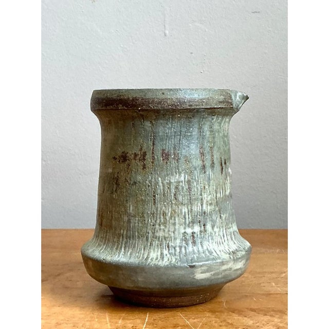 This stoneware pitcher takes a distinctly architectural, hourglass-inspired form, its body tapering inward at the midpoint...