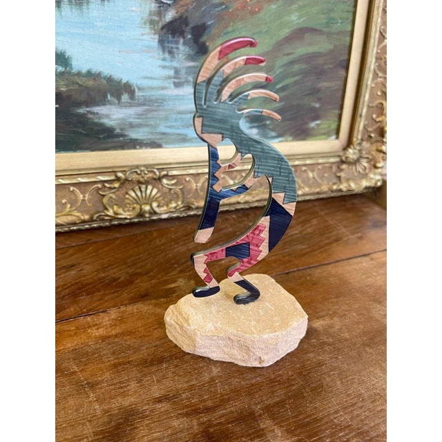 Decorative Southwestern-style Kokopelli sculpture featuring a stylized flute player silhouette with multicolored stone...