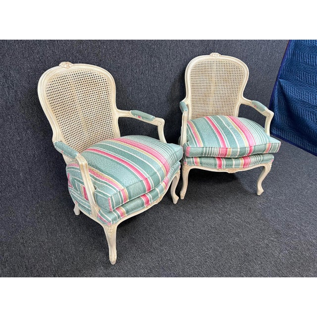 French Country pair of Louis XV style cane fauteuils with cabriole legs, newer upholstery, and carved accents.