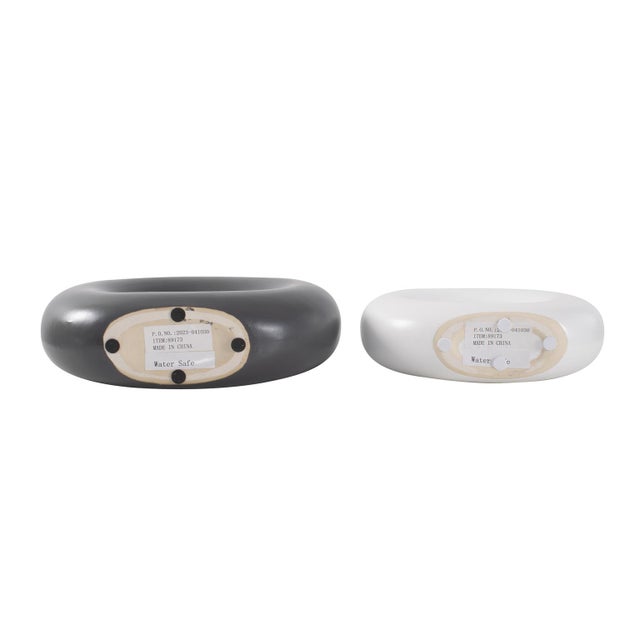 A dynamic duo comprising one matte black and one matte white circular vase. These vases stand as the ebony and ivory of...