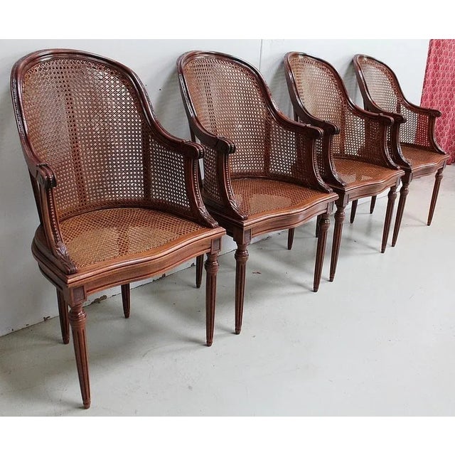 Suite of four solid mahogany and cane armchairs with curved shepherdess backs. The armrests have a molded surround with a...