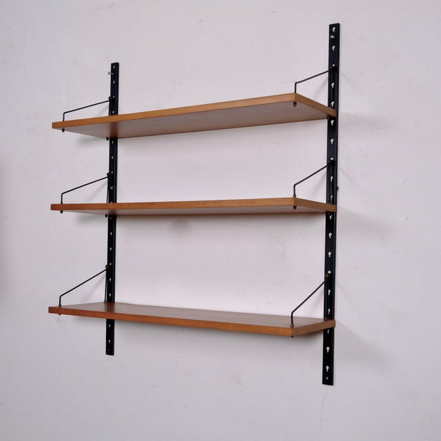 Vintage wall-mounted bookcase from the 1950s/60s, featuring wooden shelves and iron uprights. A timeless classic in mid-...