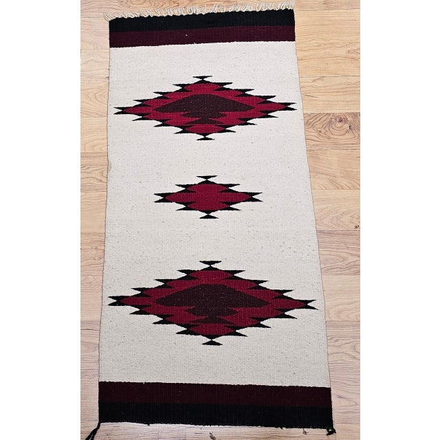 This vintage Native American Navajo area rug, woven circa the mid-20th century, features a striking triple medallion...