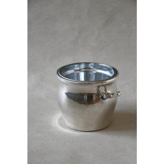 A lidded silverplate ice bucket by International Silver Co. in the Countess pattern, with a fitted glass liner that keeps...