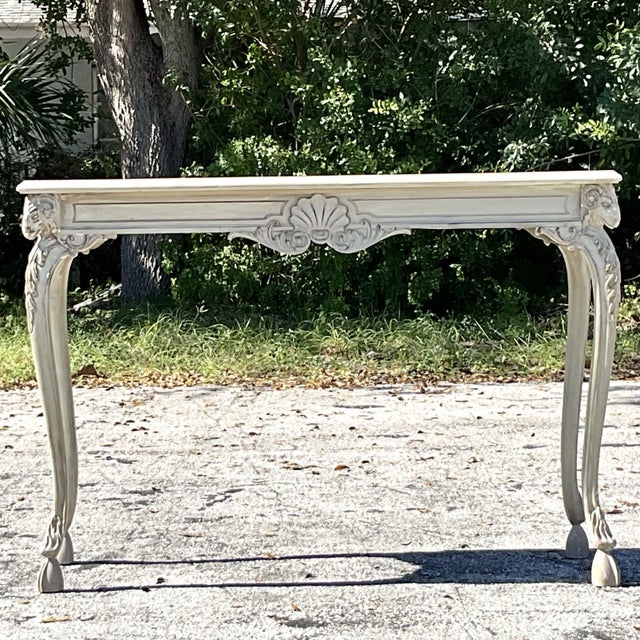 A stunning Regency-style console table showcasing masterful craftsmanship with intricately carved ram's head motifs on...