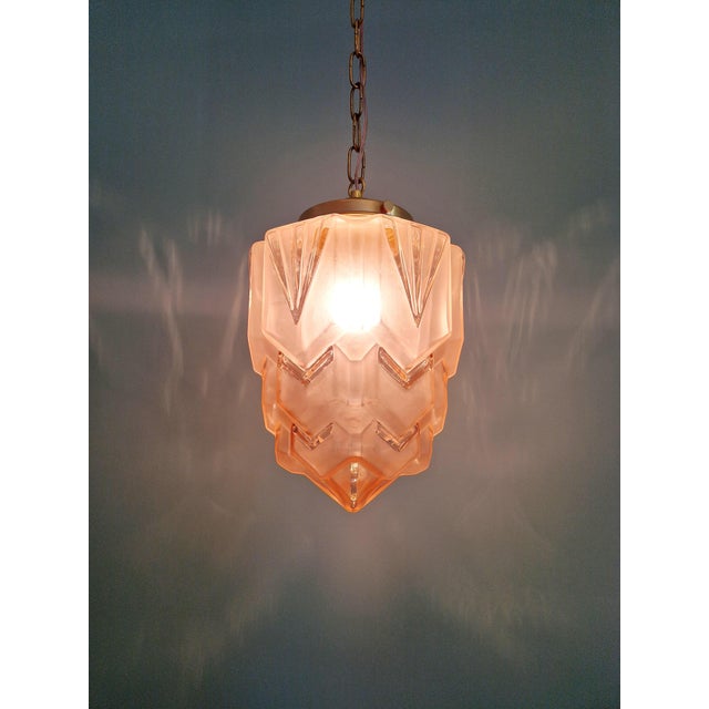 Art Deco Skyscraper pendant light in frosted pink glass with a brass mount, 1920s-30s. The pendant has been restored and...
