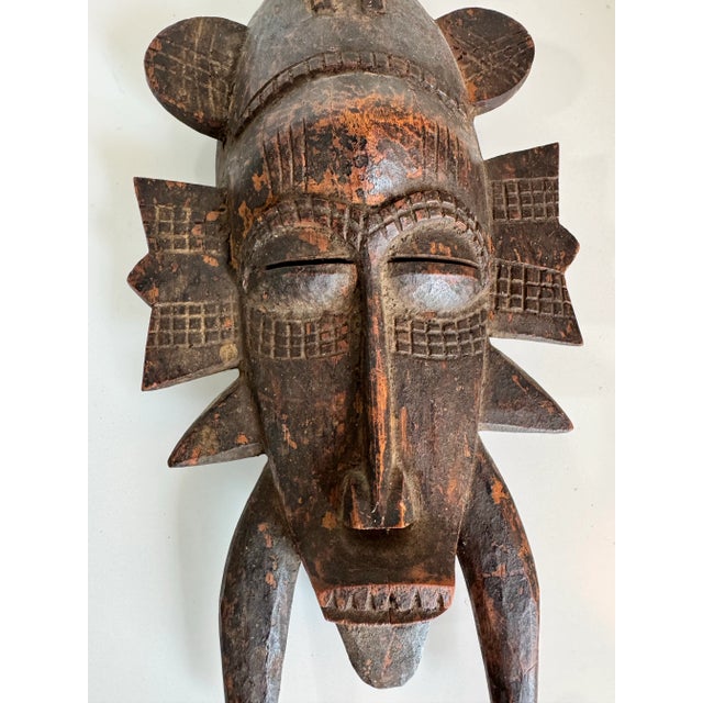 This striking vintage African mask is a hand-carved wooden piece with bold geometric detailing and deep tribal symbolism....