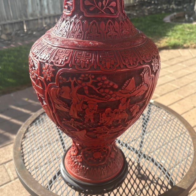 A Chinese carved cinnabar lacquer vase (converted into a lamp) decorated with four shaped panels of scholars on a...