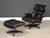 A mid century modern black leather lounge chair and ottoman with Brazilian rosewood shells designed by Charles and Ray...
