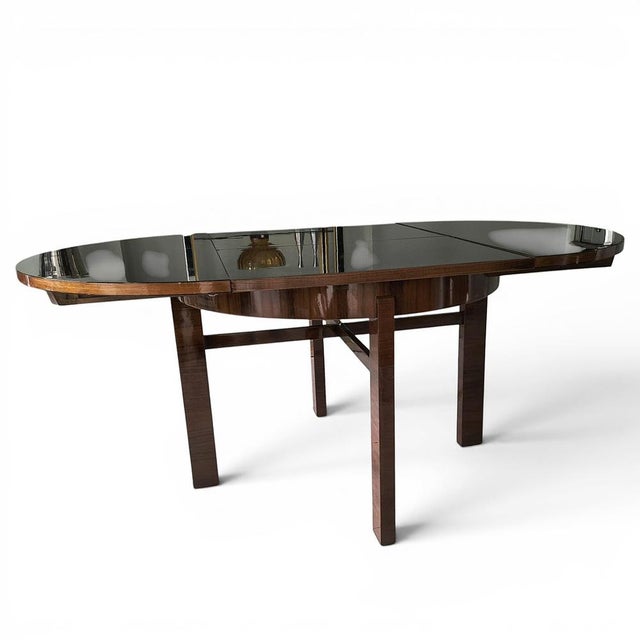 An Art Deco-style extendable table, distinguished by its elegant, timeless design and meticulous craftsmanship. The...