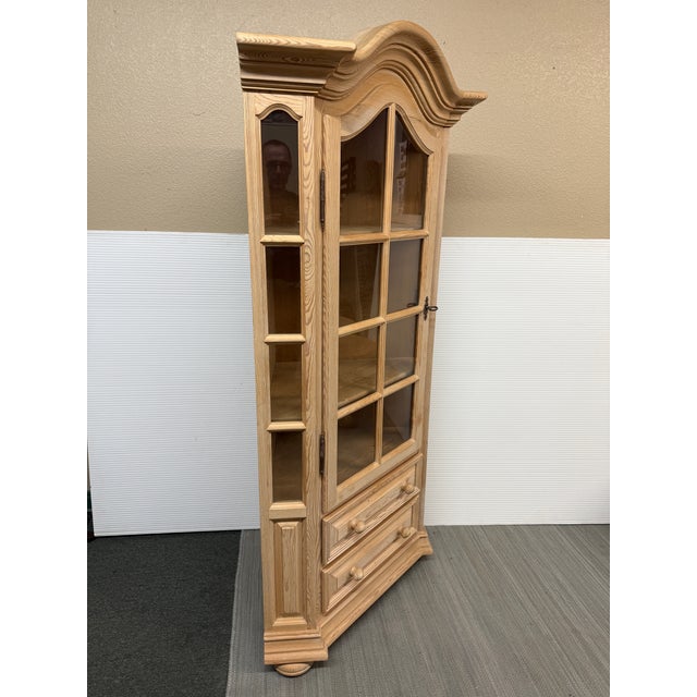 Design Plus Gallery presents a Rustic Pine Wood Corner Cabinet. The curio cabinet is made from a clean woodgrain that...