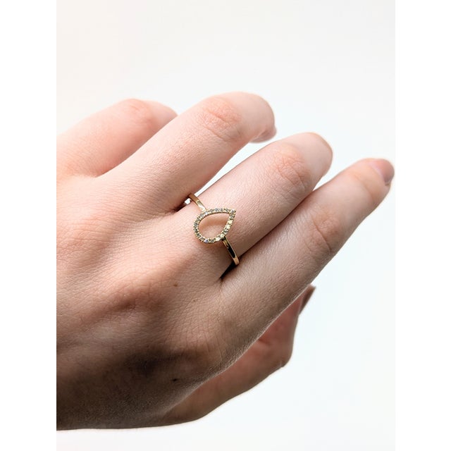 This pear-shaped halo diamond ring in solid 14K yellow gold features a striking hollow center for a fresh, unique look....