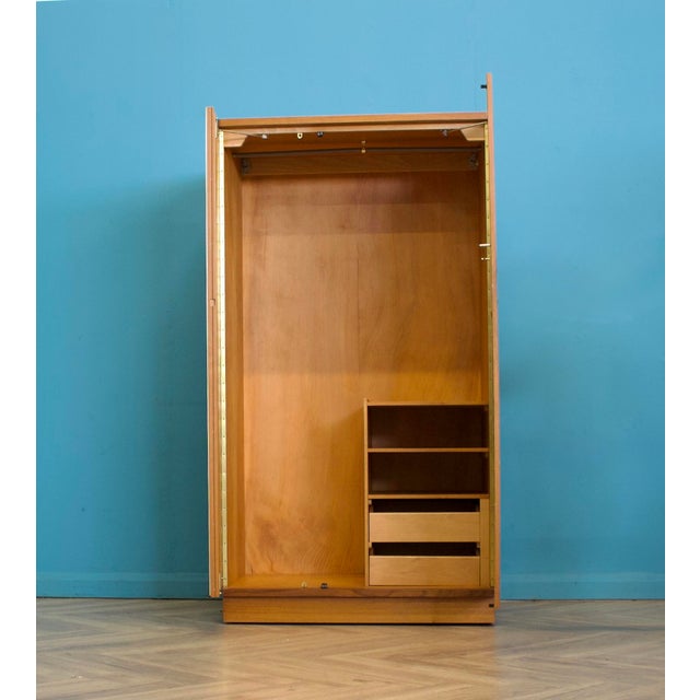 A mid century Uniflex wardrobe in warm teak veneer, with a clean front and recessed handles. Fitted with a mirrored door...
