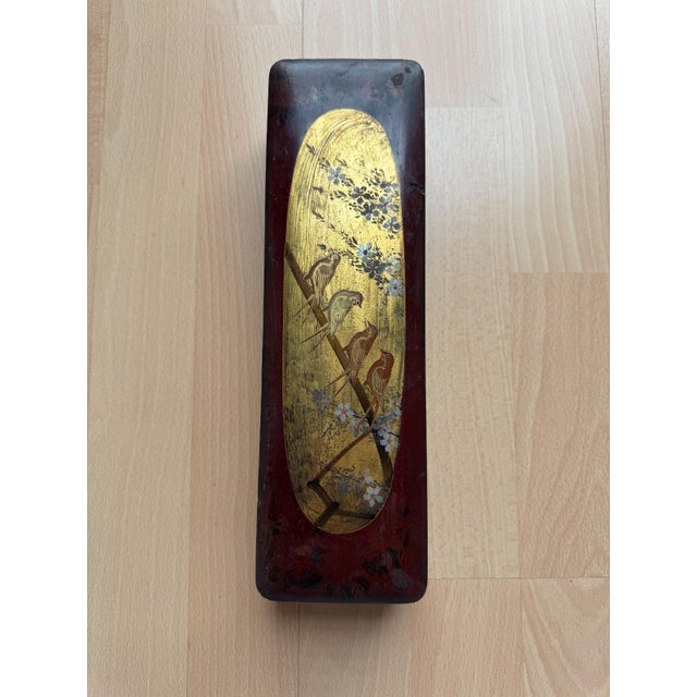 This antique, oblong japanese wooden box measures approximately 5.4 × 28.2 × 8.4 cm (h/w/d) and is lacquered in a dark...