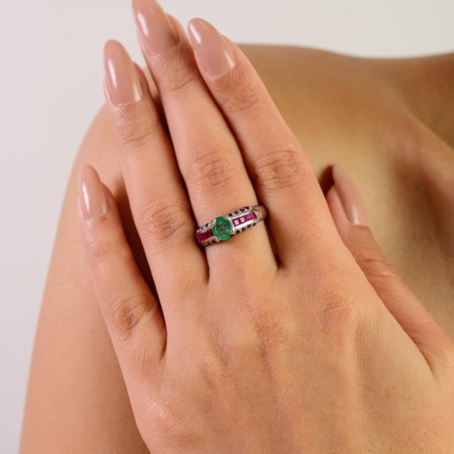 This elegant 925 sterling silver ring features a natural emerald set with ruby and blue sapphire gemstones. The ring...