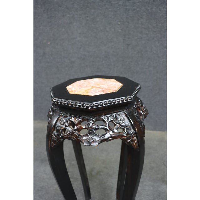 Antique Chinese plant stand crafted of dark hardwood, featuring an octagonal pink marble inset top with a beaded edge. The...