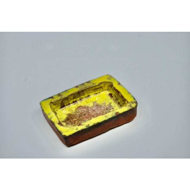 Rectangular Brutalist ceramic trinket dish with yellow and brown glaze and a crystallized glass base, signed GL (artist's...