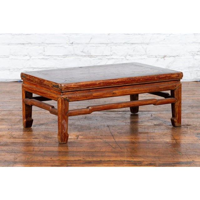 A Chinese Qing Dynasty period distressed low table from the 19th century with humpback stretchers and horse hoof feet....