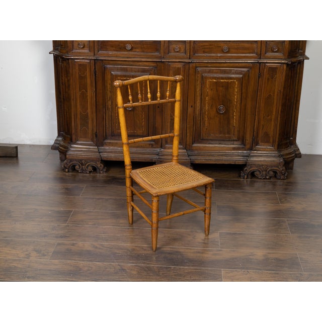 An English Turn of the Century bamboo slipper chair from the early 20th century, with cane seat. Created in England during...