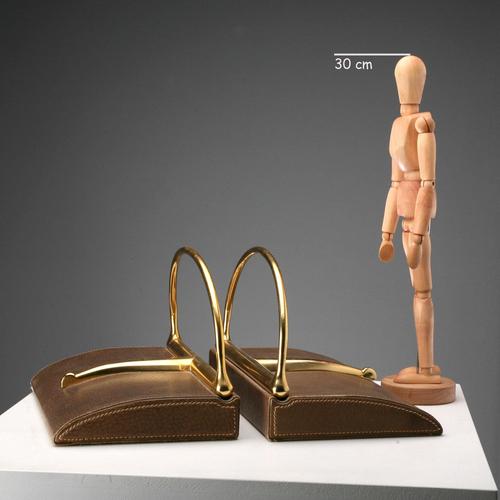 Leather and brass bookends by Gucci. Trademarked. Gucci is an Italian fashion house specializing in high fashion and...