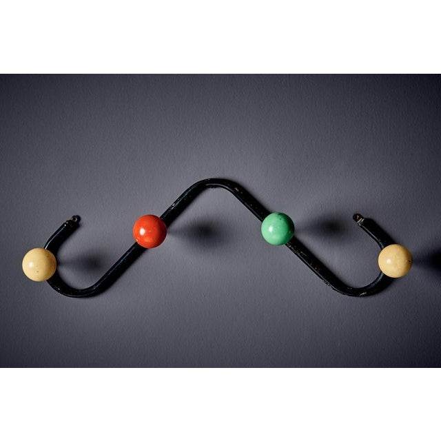 Coat hanger by Roger Feraud for GEO, featuring a black lacquered iron frame with four multicoloured wooden ball hooks, its...