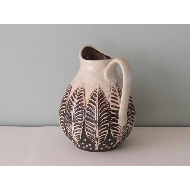 Light beige pitcher with brown and beige leaf motif. The inside of the pitcher has a dark brown glaze. The item is in very...