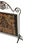 Antique iron fireplace screen featuring a floral needlepoint or tapestry panel with animal motifs set against a dark...