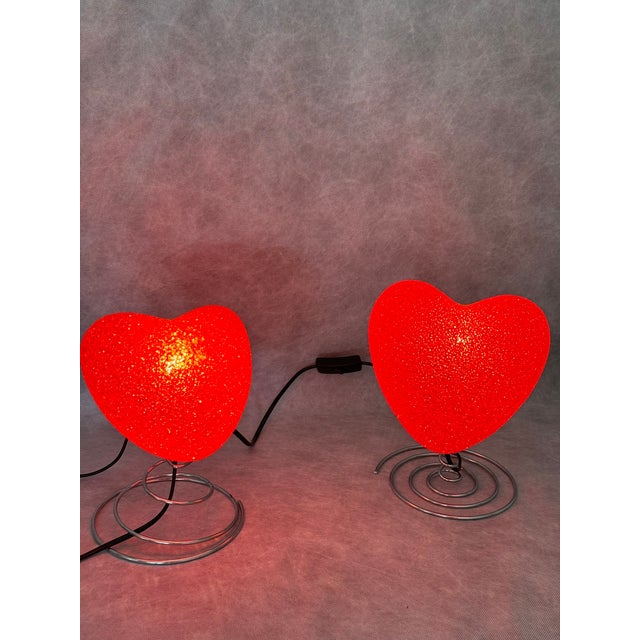 Decorative pair of heart-shaped table lamps made of translucent rubber-like plastic. A playful pop-style lighting piece...