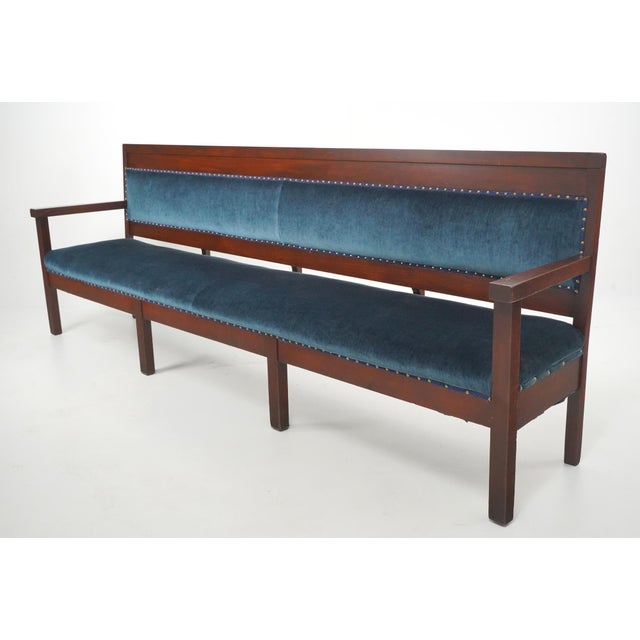 Traditional style settee bench with a dark stained walnut frame and upholstered in deep blue velvet fabric lined with...