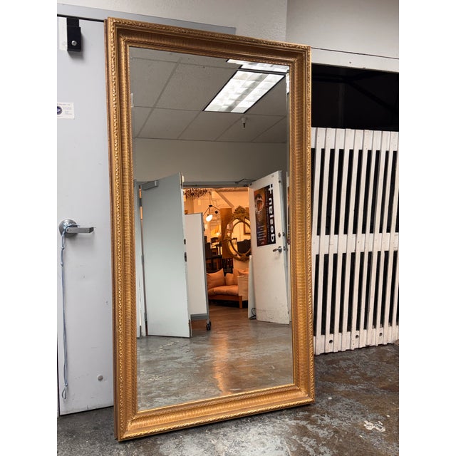 Design Plus Gallery presents a Bespoke Giltwood Beveled Floor Mirror. The tall rectangular mirror is framed by an ornate...