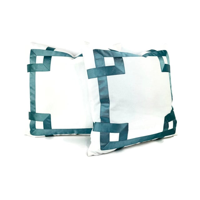 This lumbar pillow cover is white with a dark smokey blue ribbon embellishment. The ribbon forms a fretwork pattern around...