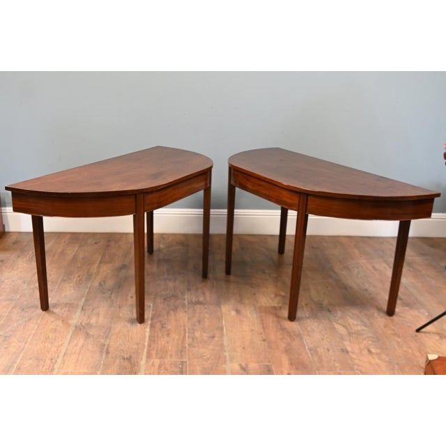 An elegant pair of Georgian mahogany demi-lune console tables dating to circa 1820 Each features a semicircular top...