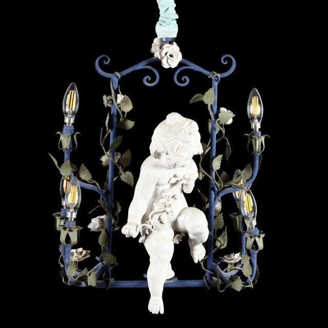 Details: -A beautiful vintage Italian chandelier featuring a charming porcelain cherub (putti) set within an elegant navy...