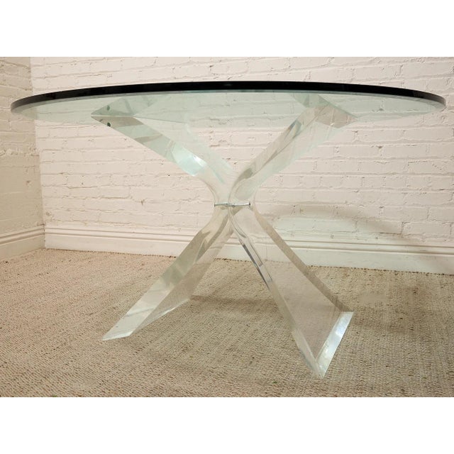 A striking vintage dining table with a dramatic sculptural Lucite base and clear glass top. The pedestal is formed from...