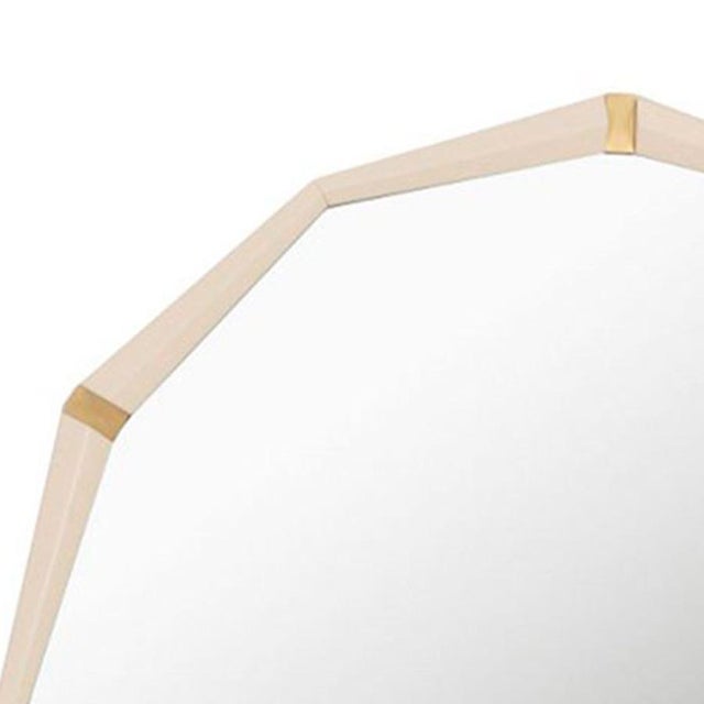 This large modern mirror features a dedecogan shape with a ivory lacquer frame. Sophisticated accents of recessed brushed...