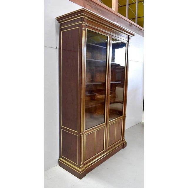 Louis XVI style solid and veneered Cuban mahogany bookcase, richly upholstered in brass. It opens with two doors, 3/4 of...