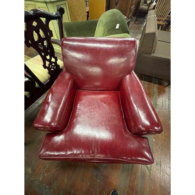 Classic vintage club chair and ottoman upholstered in rich burgundy leather with deep, cushioned comfort and timeless...