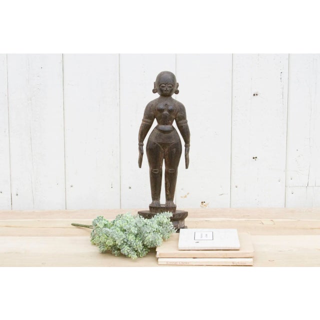 The sculpture is a very old wooden shrine idol, showing a deep, well-handled surface patina and signs of wear from many...