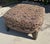 Substantial vintage upholstered ottoman featuring a generously cushioned top, richly patterned damask upholstery, and...