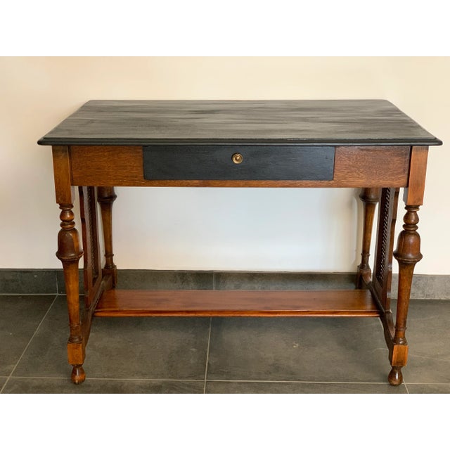 A late 19th century library desk table with an ebonized oak top and drawer. The caned sides are handcrafted and in...