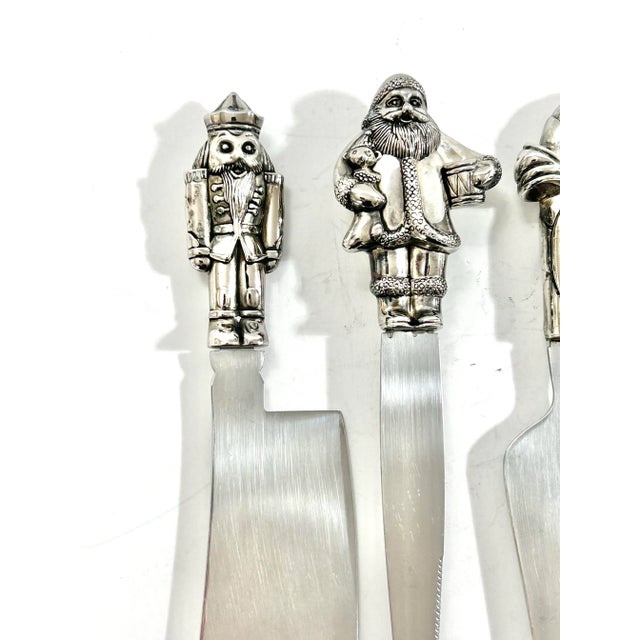 Vintage 1990s Wallace Silversmiths Christmas cheese serving set featuring three stainless-steel utensils topped with...