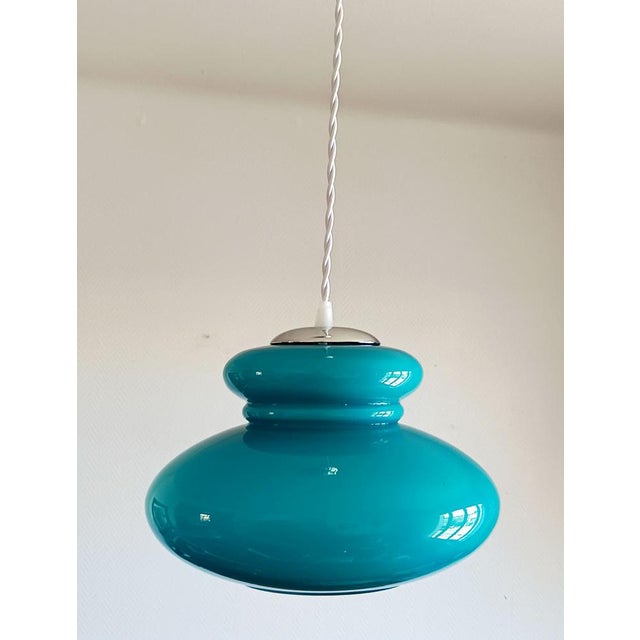 Vintage pendant light, circa 1970, featuring a blue glass globe in a UFO shape. Rewired with a new silver-plated metal...