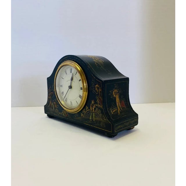 Black painted Walker and Hall mantle with chinoiserie decoration and a round brass ring face painted white with black...